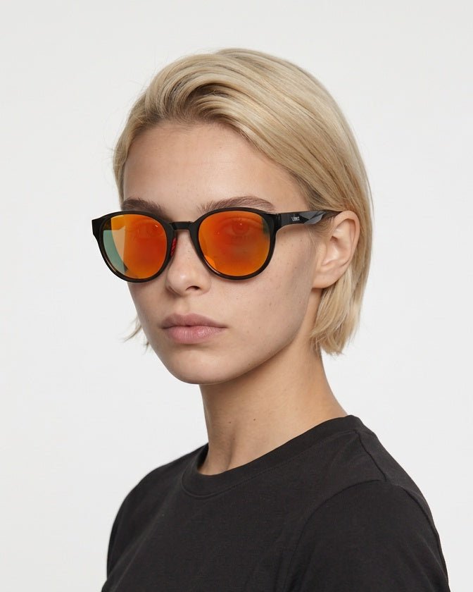Hollis retro round sunglasses in Orange / Black, orange lens on black frame, worn by a woman, front view