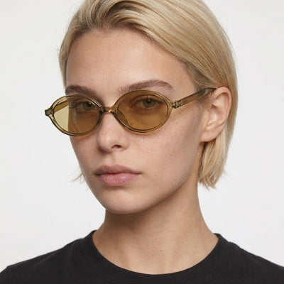Mojave slim oval metal sunglasses in Gold / Gold, gold lens on gold frame, worn by a woman, front view