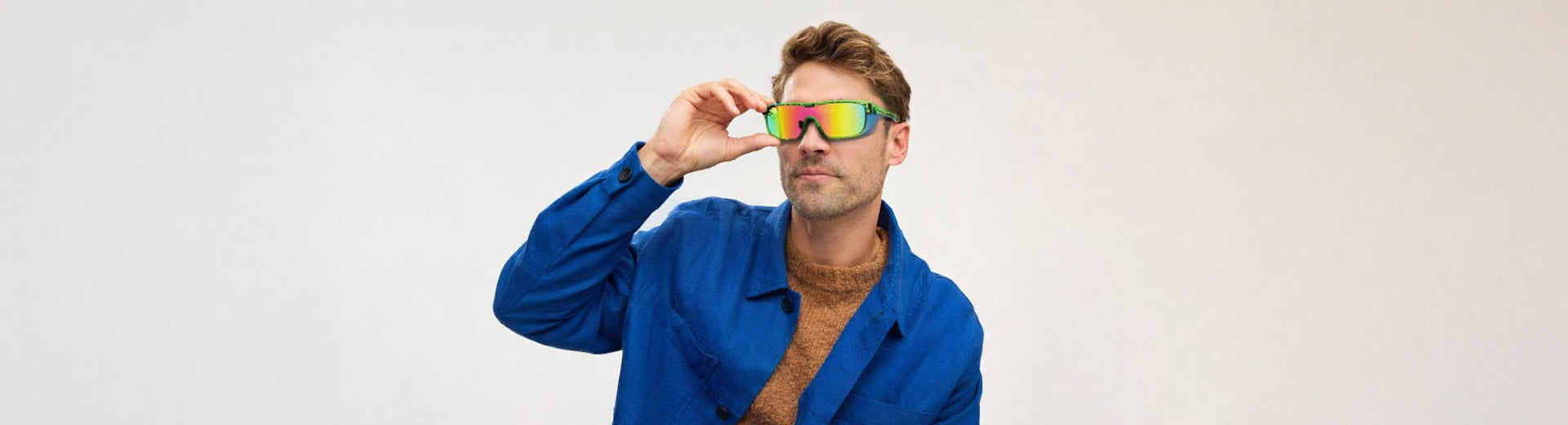 Man wearing a blue robe and colorful sunglasses against a plain background