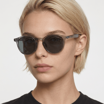 Onyx round retro sunglasses in Black / Clear Grey, black lens on clear grey frame, worn by a woman, front view