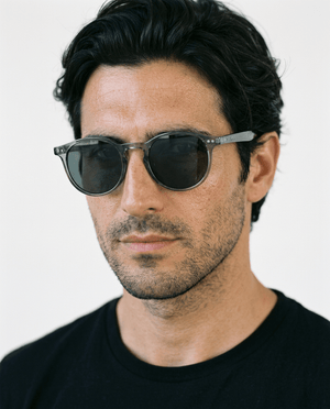 Onyx round retro sunglasses in Black / Clear Grey, black lens on clear grey frame, worn by a man, front view